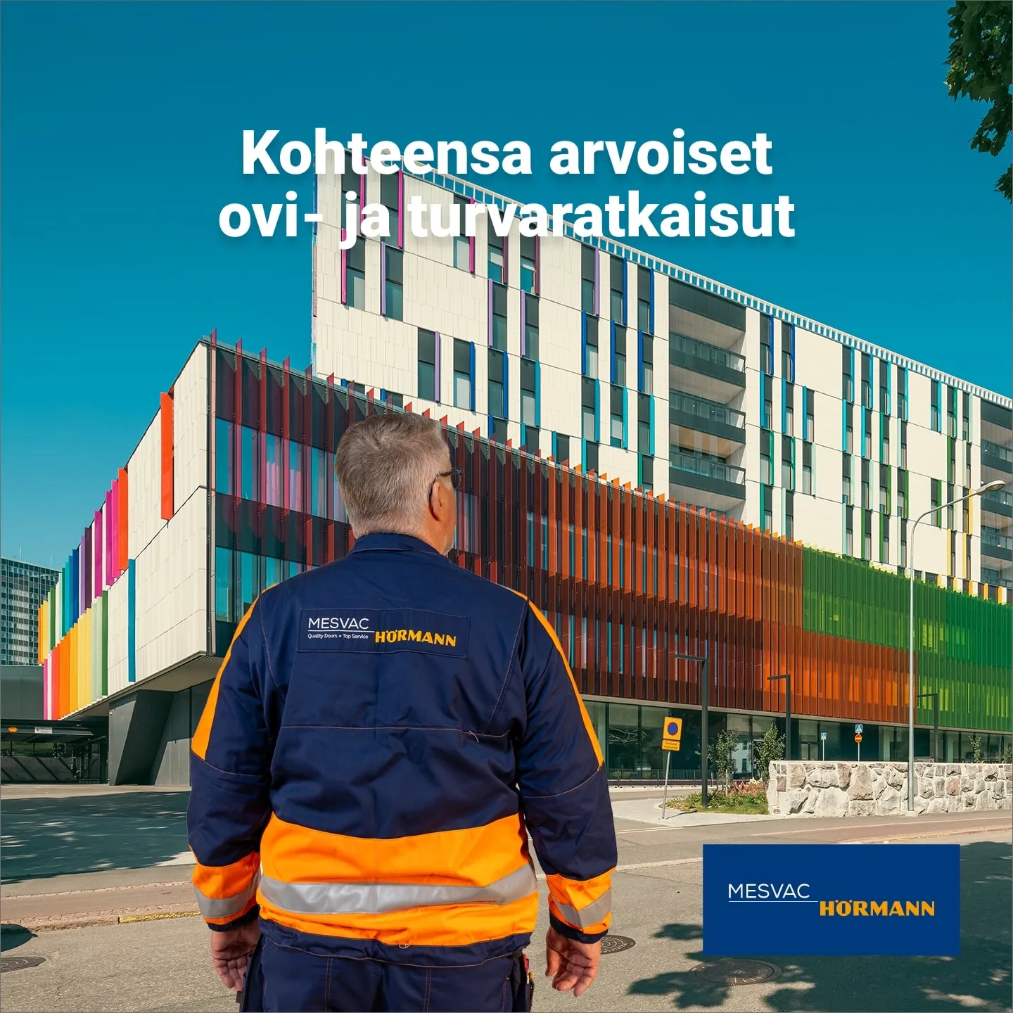 A Mesvac Hörmann installer seen from behind looking at the colourful facade of the New Children’s Hospital, with the ad line Door and safety solutions worthy of their site