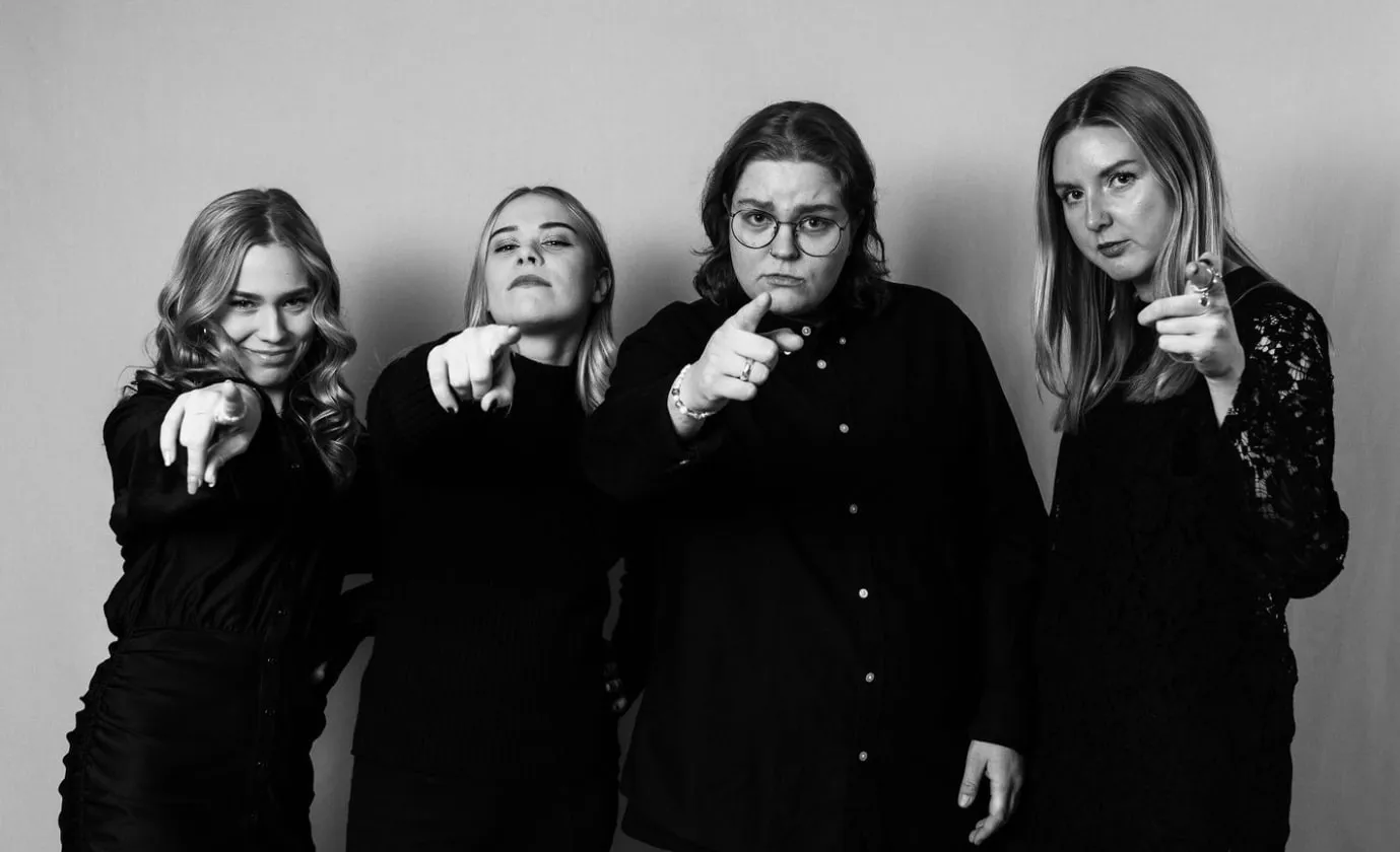 Neljä Julkee x Lempeen tiimiläistä osoittaa sormella kohti katsojaa