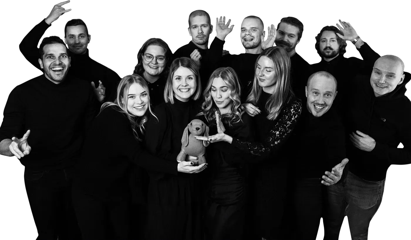 The Julkee x Lempee team in a black-and-white group photo: happy people in black clothes, with a cuddly toy dog in the middle